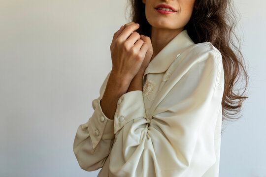 Woman with hands clasped posing against wall at home