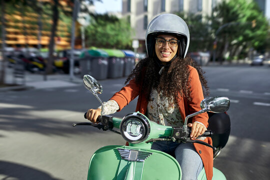 Smiling Woman Riding Electric Motor Scooter In City During Sunny Day