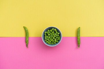 Studio shot of two green pea pods and bowl of green peas