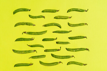 Studio shot of green pea pods against yellow background