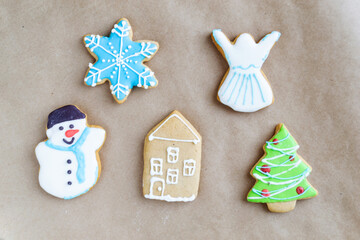 Gingerbread painted colored gingerbread cookies and spices and snowflakes on a craft background close-up. Christmas celebration concept. New Year's food