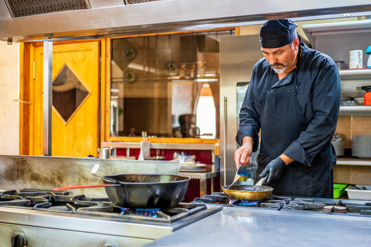 Chef with pan in traditional Spanish restaurant kitchen