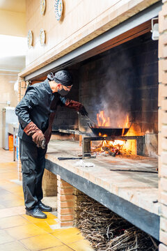 Traditional cooking of paella in restaurant kitchen, chef wearing protective mask