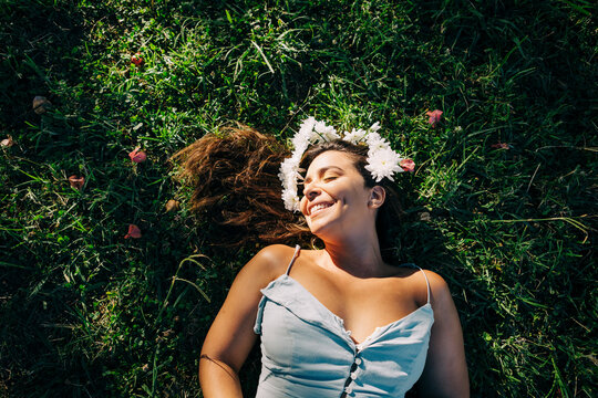 Young woman with eyes closed relaxing on grassy land in park during sunny day