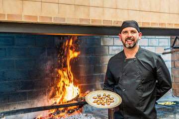 Traditional cooking in restaurant ktichen, chef showing plate with grilled seafood
