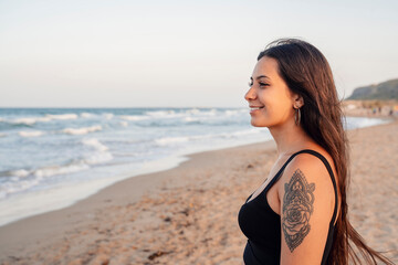 Fototapeta na wymiar Happy teenage girl standing at beach against clear sky