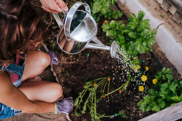 Woman crouching by man watering plants in community garden