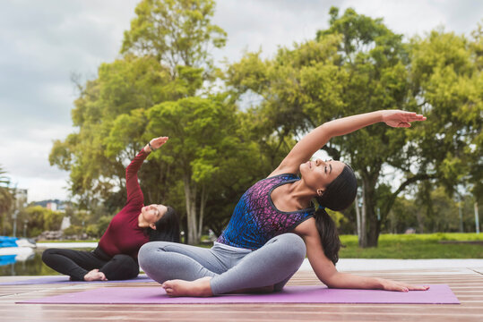 Active women practicing yoga against trees at park