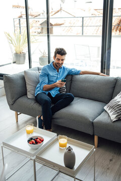 Relaxed Man Using Smartphone On Couch