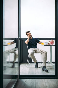 Content man on modern terrace with breakfast on table