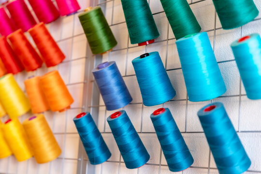 Close-up of colorful thread spools on rack at design studio