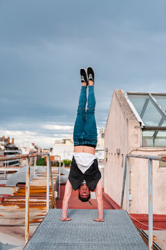 Stylish bboy performing a break dance stance in a metal staircase in the rooftop of a building 