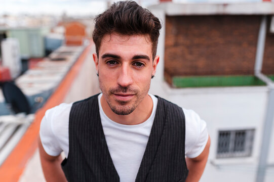 Portrait of a handsome man leaning on an iron handrail in the rooftop of a building