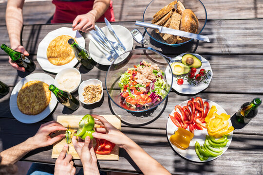 Hands of man and woman cutting bell pepper at table during brunch