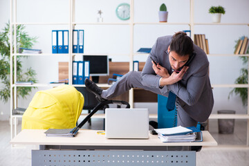 Young male employee looking after newborn at workplace