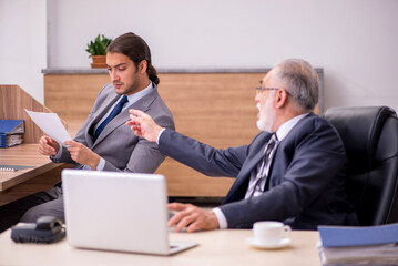 Old boss and young male assistant in the office