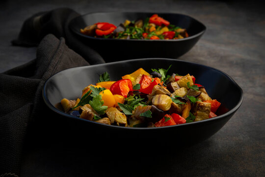Two bowls of¬†stir-fried¬†vegan salad with eggplants, paprika and parsley