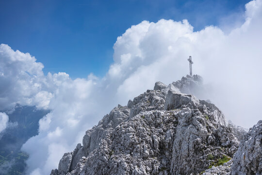 Low angle view of religious cross on mountain top against cloudy sky, Bergamasque Alps, Germany