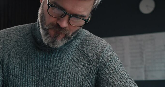 Middle aged Handsome Architect working at his Office with Ruler and Pencil, Looking serious. Having Confident look and thinking about his Project. Hard working with Drawings and Blueprints.