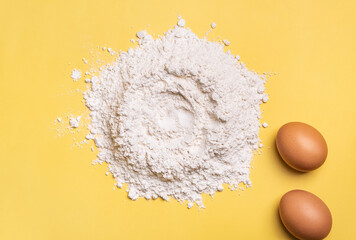 Egg and flour with space for text on yellow background. Cooking ingredients for baking. Kneading dough for pastry.  Copy space.