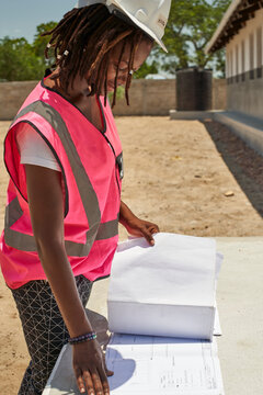 Female architect analyzing blueprint on table while standing at site during sunny day