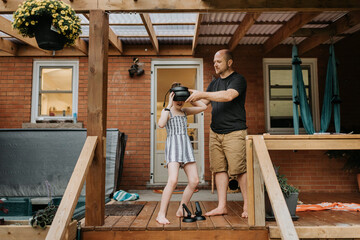 Father wearing virtual reality simulator to daughter while standing outside house