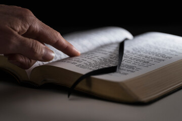 Human finger on open Bible