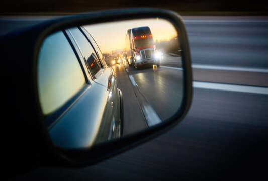 Truck on road reflecting in rear view mirror