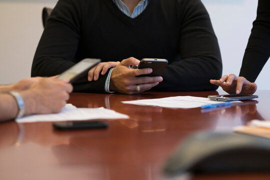 Mid section of business people using mobile phone