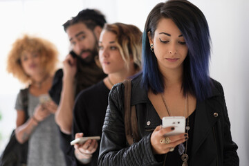 Young people standing in line using smartphones