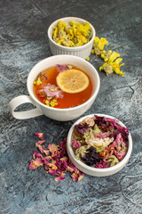 front view herbal tea with dry flowers and a plate on grey ground