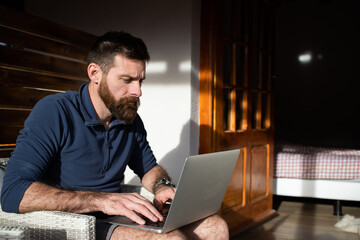 man working on laptop in wooden cottage