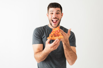 Attractive man taking a bite of a tasty slice of pizza
