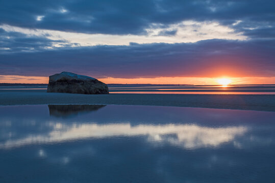 USA, Massachusetts, Cape Cod, Orleans, Rock reflecting in sea at sunset
