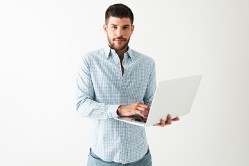 Latin young man is standing and working on a laptop