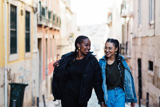 Portugal, Lisbon, Two smiling young women walking outdoors