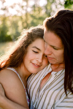 Smiling mother talking to daughter while embracing in yard