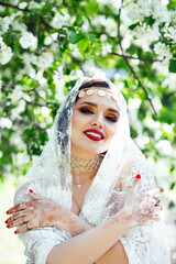 young pretty indian girl in jewelry and veil posing cheerful happy smiling in green park, lifestyle people concept