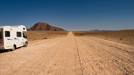 Camper road trip in Namibia - endless straight gravel road washboard in the plains of Namib...