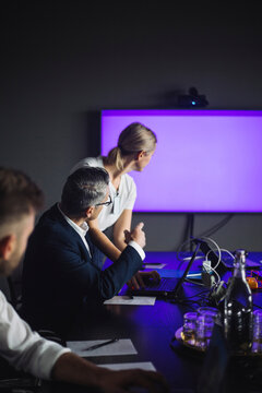 Male IT professional pointing at projection screen by female colleague at workplace