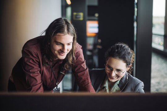 IT professional discussing with smiling female colleague in office