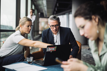 IT professional assisting contemplating businessman in office corridor