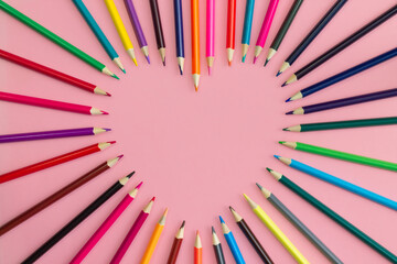 Heart laid out with sharpened multi-colored pencils on a pink background, flat lay, copy space. - obrazy, fototapety, plakaty