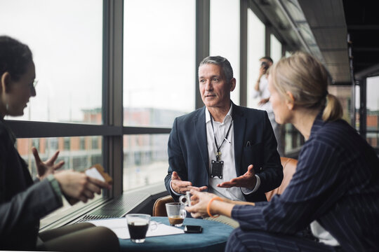 Female IT professionals discussing with businessman in office corridor