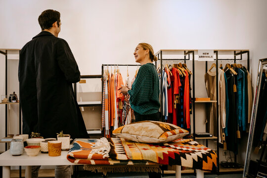 Smiling female owner showing clothing to customer in store