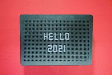 Hello 2021 on message board. Flat lay style. New Year greetings. Red background. 