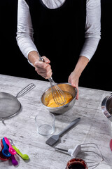 female cook working beating eggs with her hands. Concept of cooking and baking at home, blog, classes, social networks and small businesses. Vertical photo and selective focus.