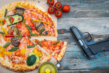 gustosa pizza alle verdure alla griglia vicino a una pistola su fondo in legno.