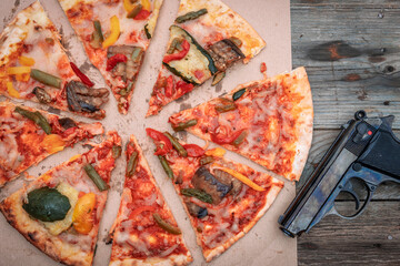 gustosa pizza alle verdure alla griglia vicino a una pistola su fondo in legno.