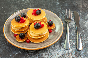 Close up view of fruit pancakes next to fork and knife